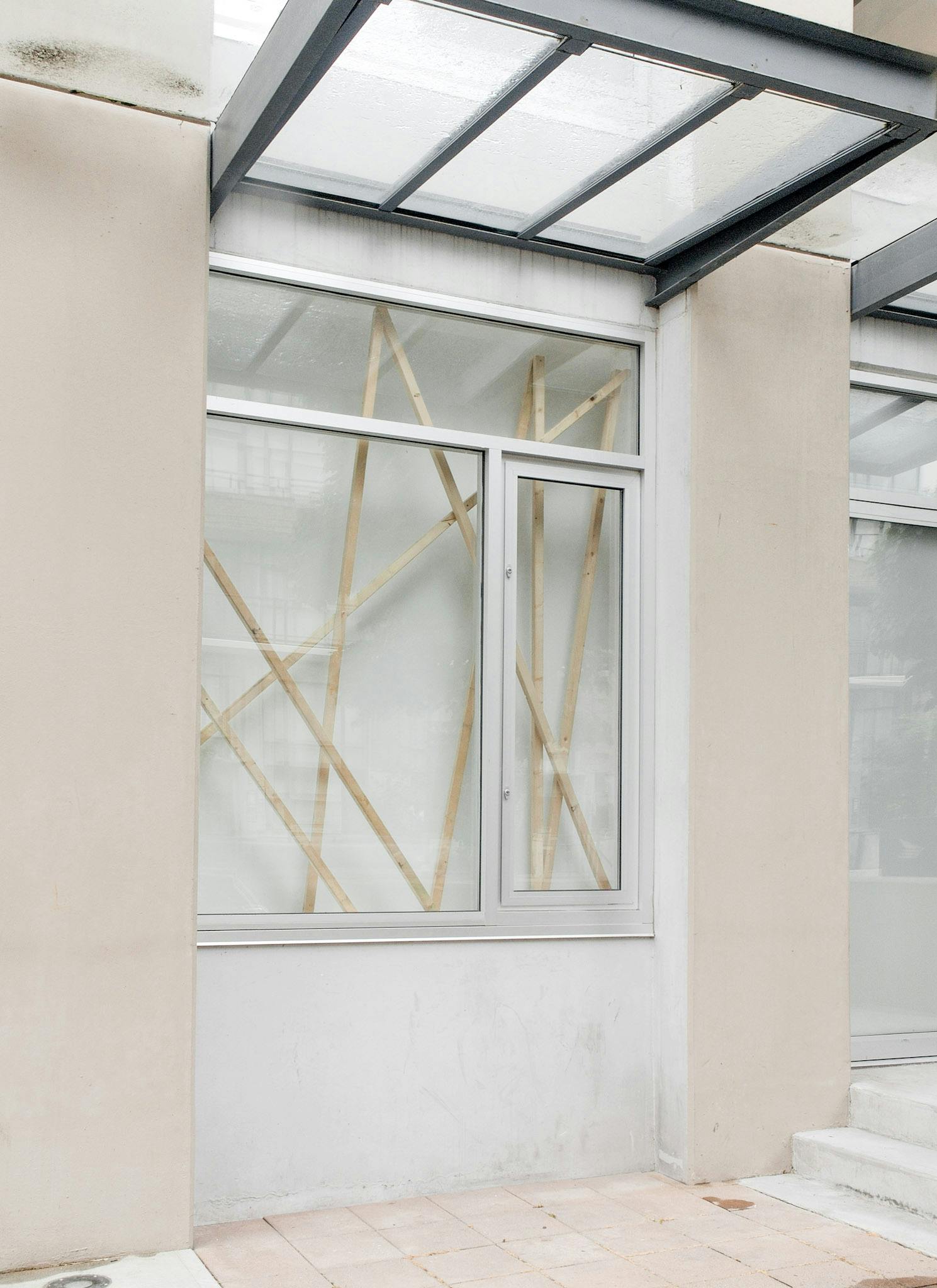 This image shows one of CAG’s window spaces, in which Elspeth Pratt’s installation art is displayed. Eight thin wooden bars are inserted in the window space diagonally to create a rough fence.  