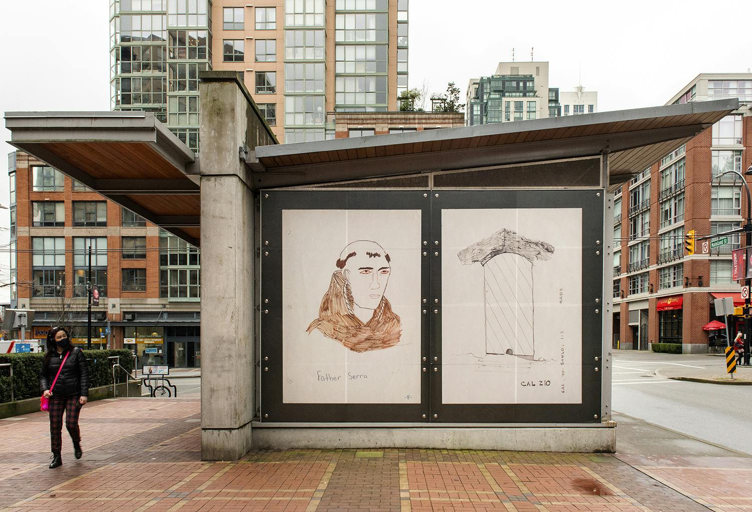 An exterior view of a train station displaying Sandoval’s work printed in vinyl. The work depicts an illustration of a Fransiscan friar on the left and on the right an enlarged drawing of a doorway. 