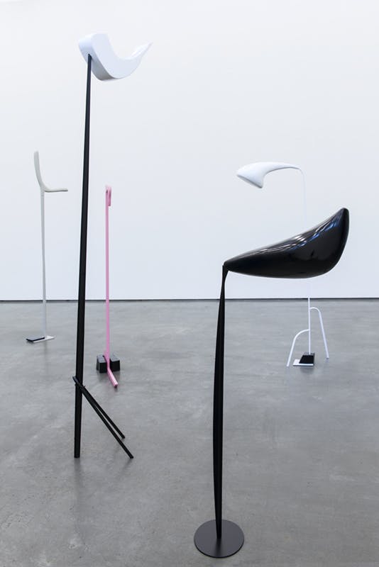 Nairy Baghramian's sculptures installed in a gallery  Some of the black and white sculptures are larger than human-scale. Their rounded heads are supported by thin straight necks.