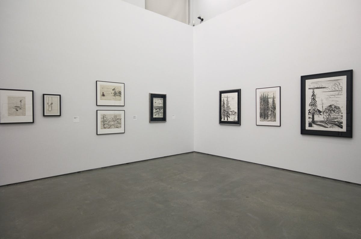 Eight framed works on paper mounted on two gallery walls. Five on the left side of a corner wall and three on the right, varying in scale. The artworks depict outdoor settings and trees.