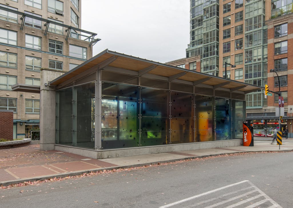 A photographic mural in vinyl is installed on the windows of Yaletown-Roundhouse Station. Black dots scatter across a semi-translucent background of softly focussed yellows, blues and greens.