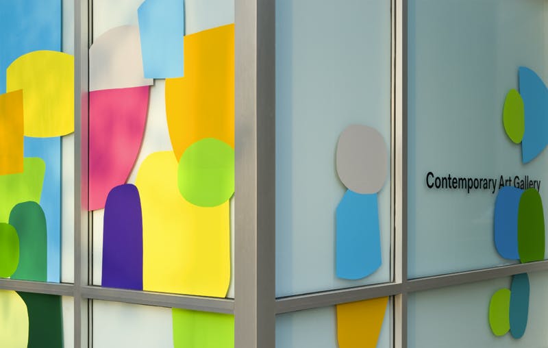 This is a close-up shot of the corner of CAG’s building taken from outside. The first floor windows are covered with colourful circular shapes overlapping with each other in a light blue background.  