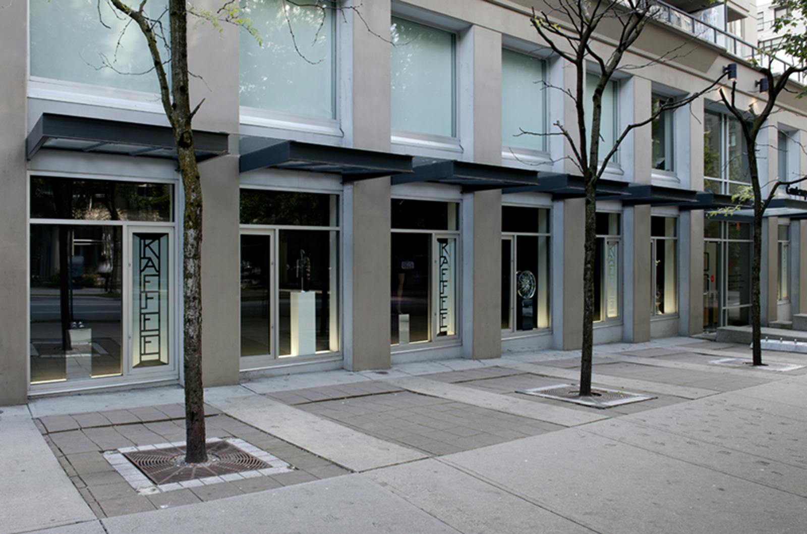 Josephine Meckseper’s sculptures installed in CAG’s facade windows. A narrow stained-glass piece, which has a design that reads KAFFEE on, is installed on the right side of some of the sculptures.