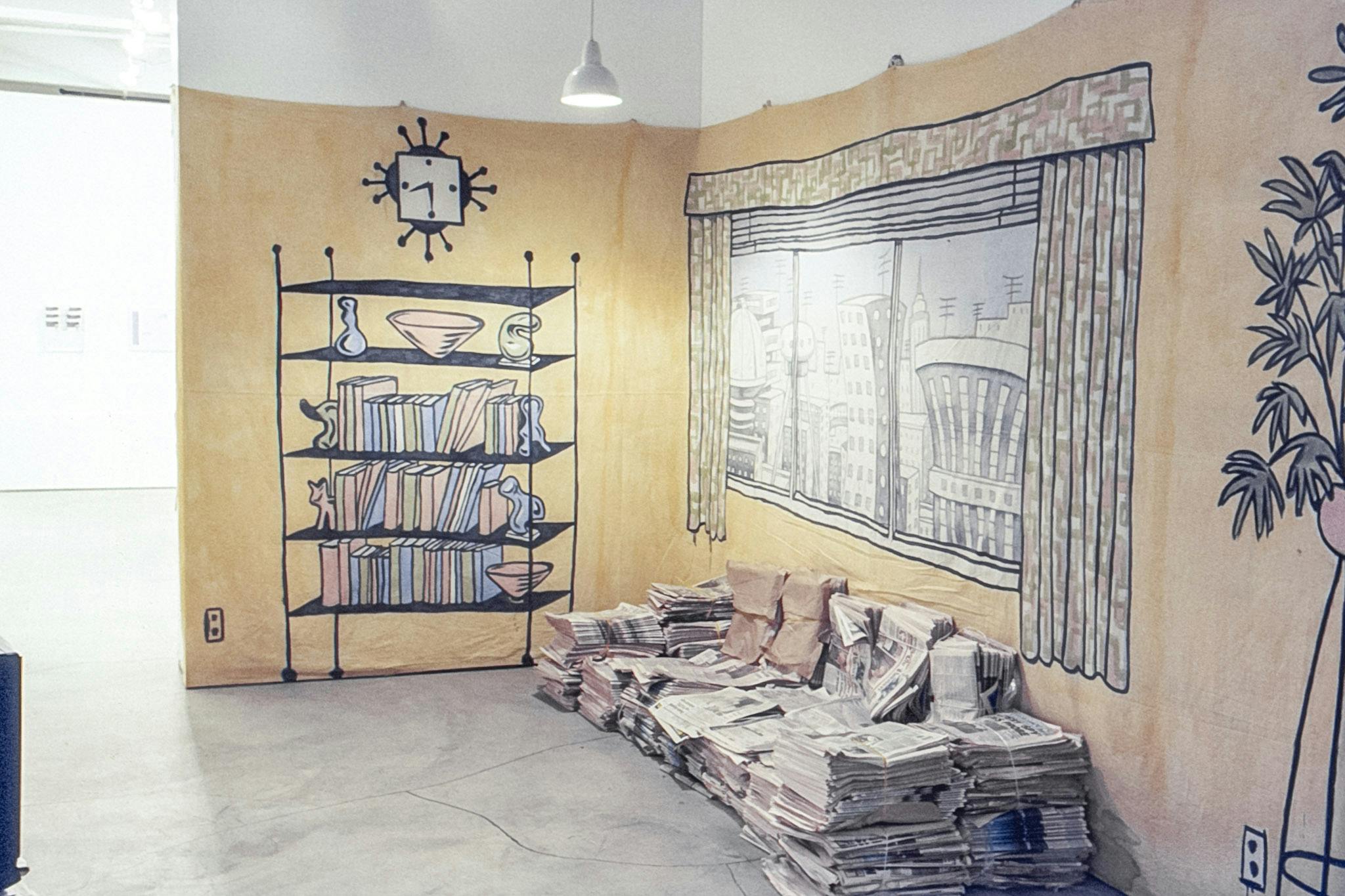 In the corner of a gallery, there is a large piece of fabric painted as a home (with a window, bookshelf, and plant stand) hung on the wall. At the base of the wall, stacks of newspaper form a couch. 