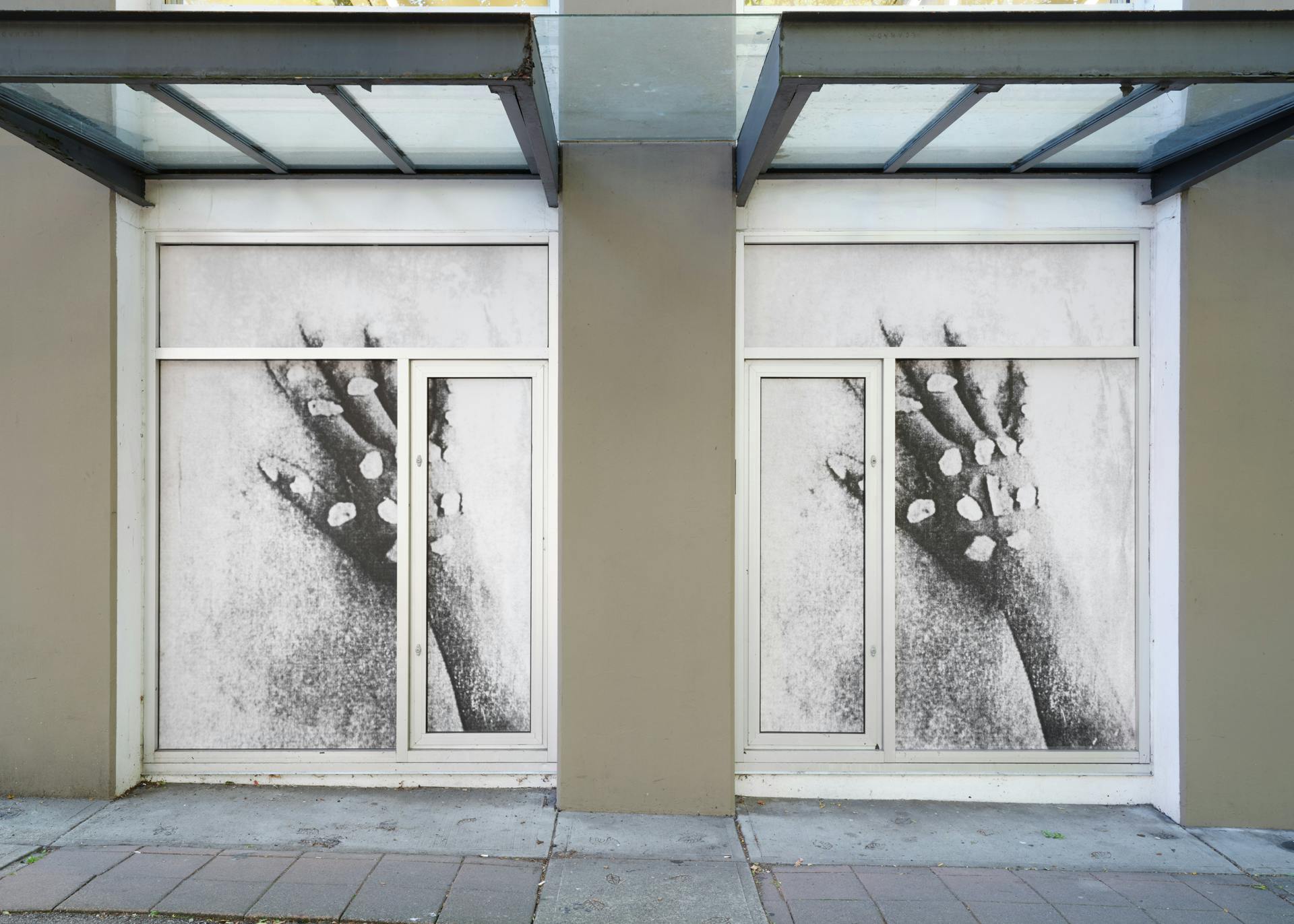 A pair of windows featuring a pair of images depicting a hand with small white pebbles placed on its joints. Both images are legible, with the right image slightly darker than the left one.