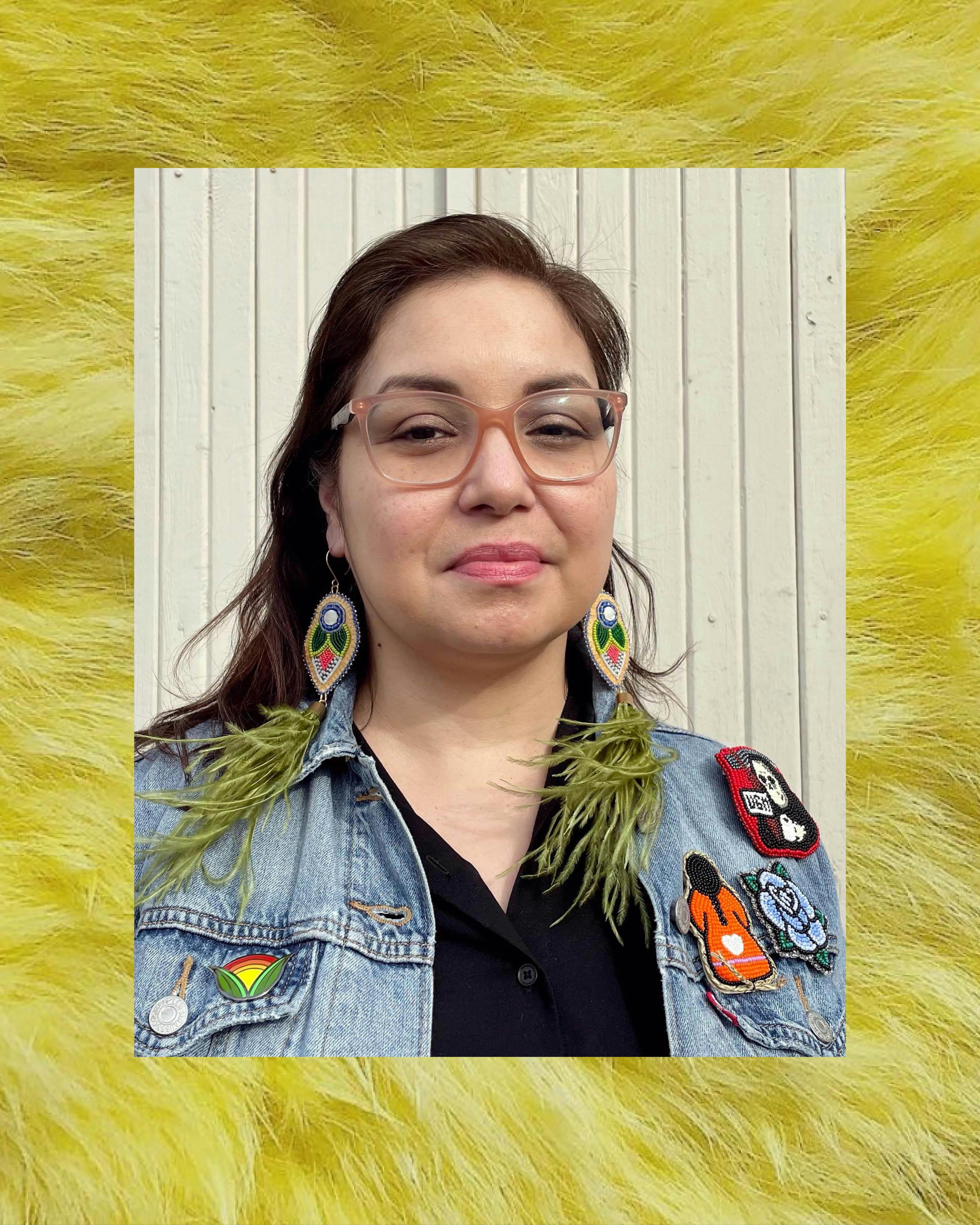 A portrait photograph of Michelle Sound. Michelle wears a pair of pink glasses and beaded earrings. The photograph is framed by a detail of her rabbit-hair drum. 