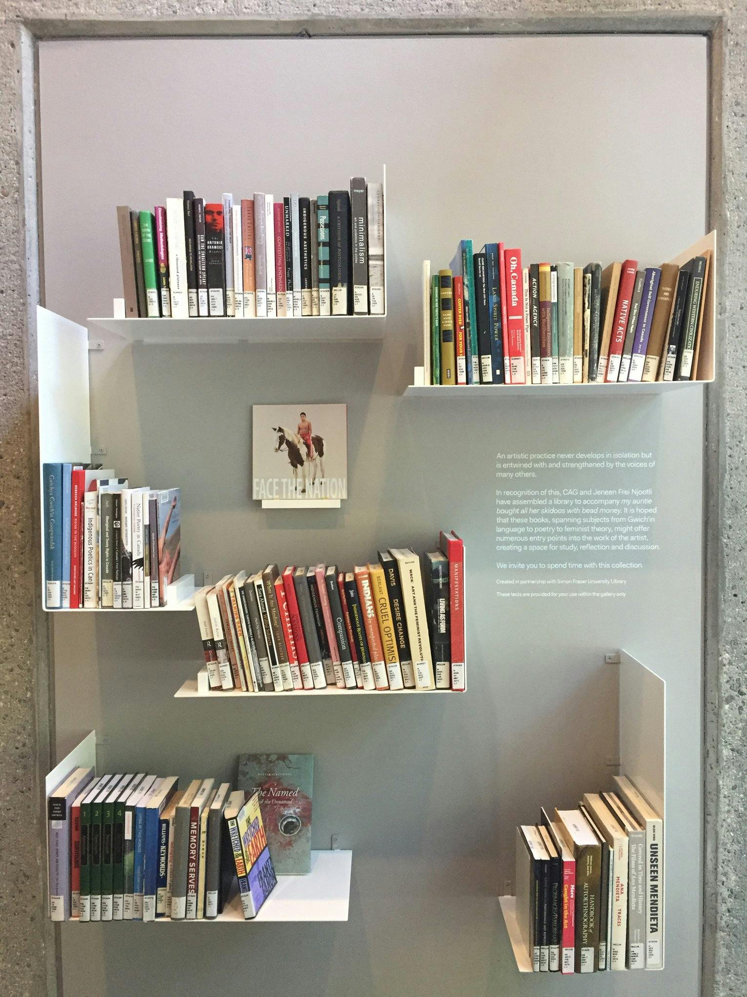A photograph of white bookshelves attached to a wall. Multiple books are installed on these bookshelves. 
