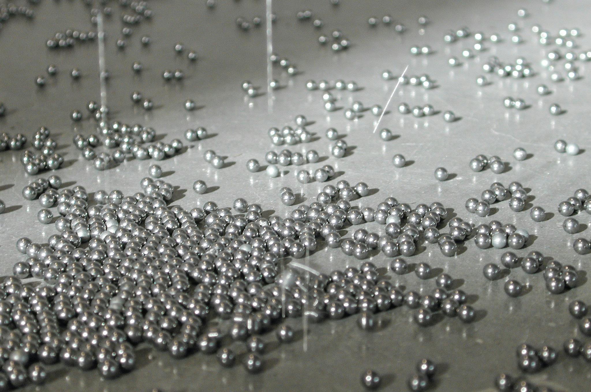 A number of small steel balls for pinball are scattered on the gallery floor. This is a detailed view showing a collection of steel balls reflecting light in various directions. 