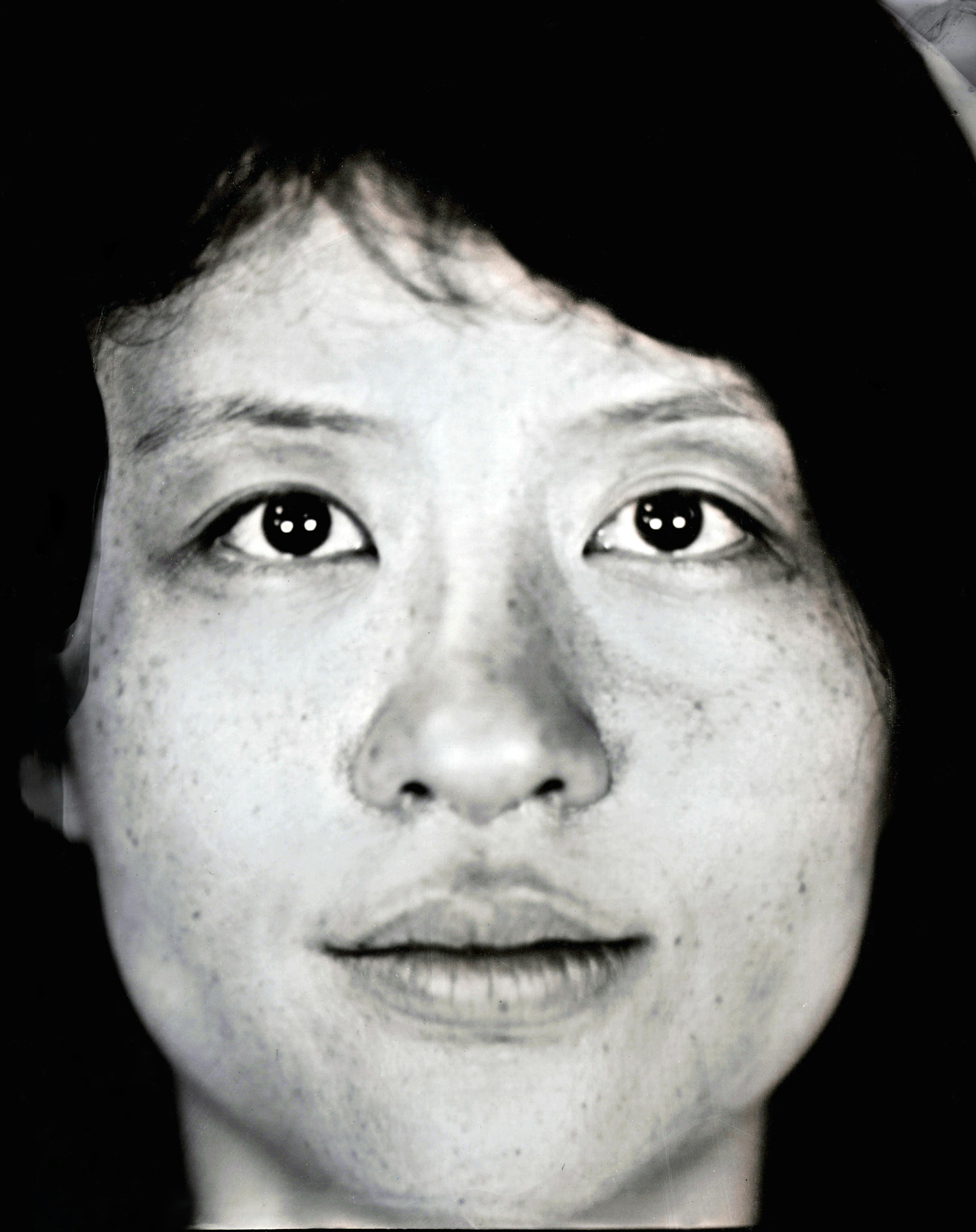 A black and white portrait of Phoebe Bei. It is closely cropped to frame her face. She is looking directly into the camera.