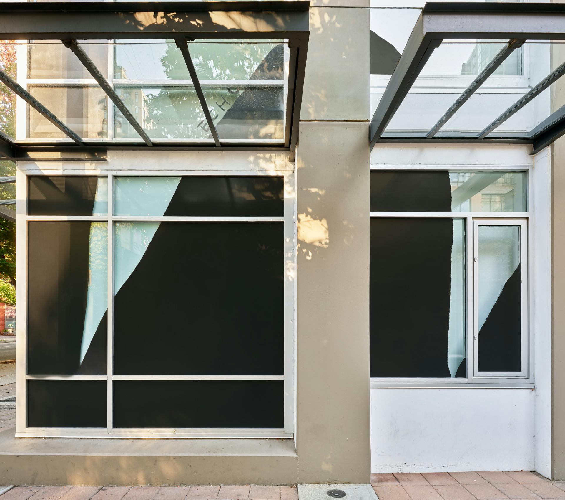 Facade of CAG with four windows in a 4 by 4 grid visible in frame. Black and white drawings by Christine Sun Kim featuring the word "echo" across the windows.