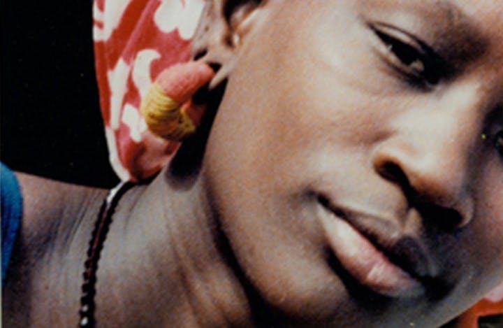 A close-up photo of a Senegalese woman facing the camera with a neutral expression.