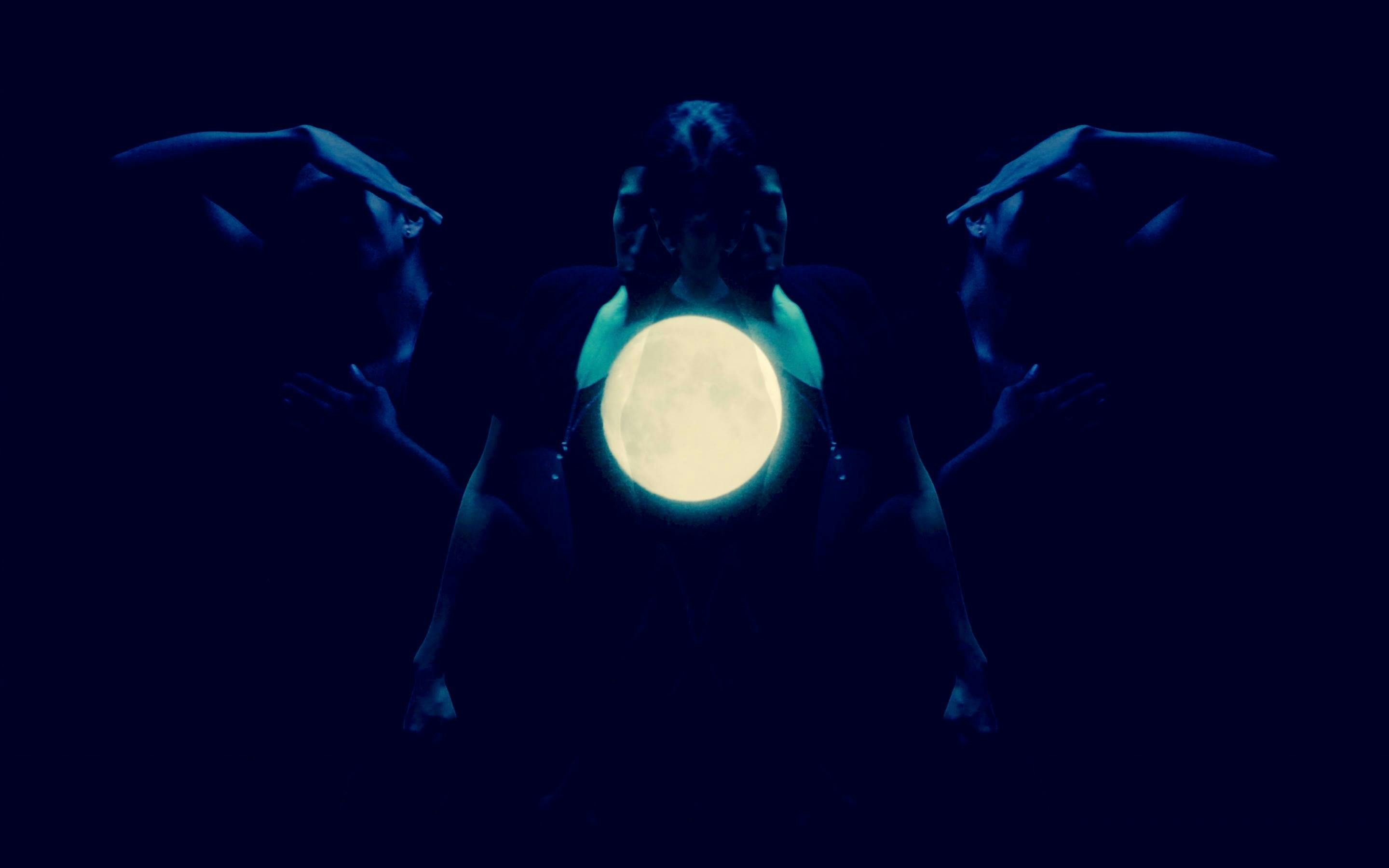 A still image from Beric Manywounds's film titled Tsanizid (Wake Up). Several animal-like shaped black objects are flowing around the full moon at night. 