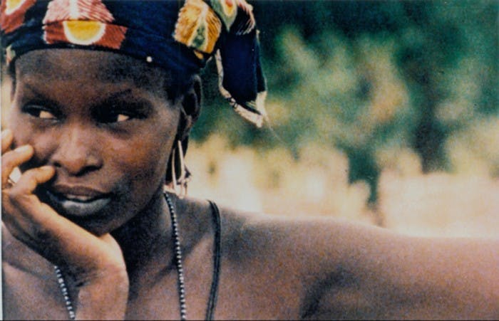 A photo of a Senegalese woman looking to her right with one arm outstretched and her chin in her other hand.