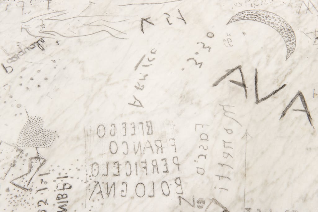 A close up image of a marble slab with writing, images and symbols hand-carved into it.