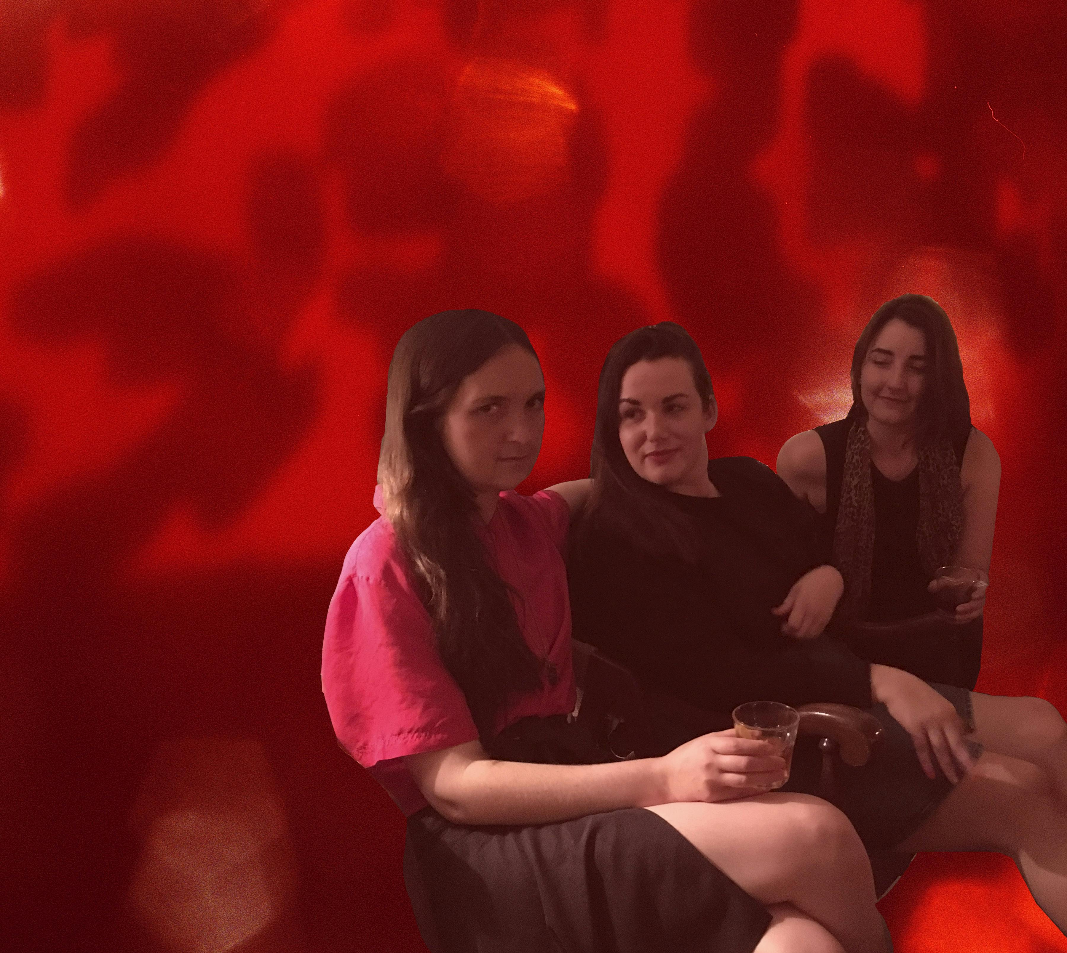 A photograph of Nicole Kelly Westman, Peta Rake, and Katarina Veljovic sitting in a row in front of Nicole’s red curtain. 